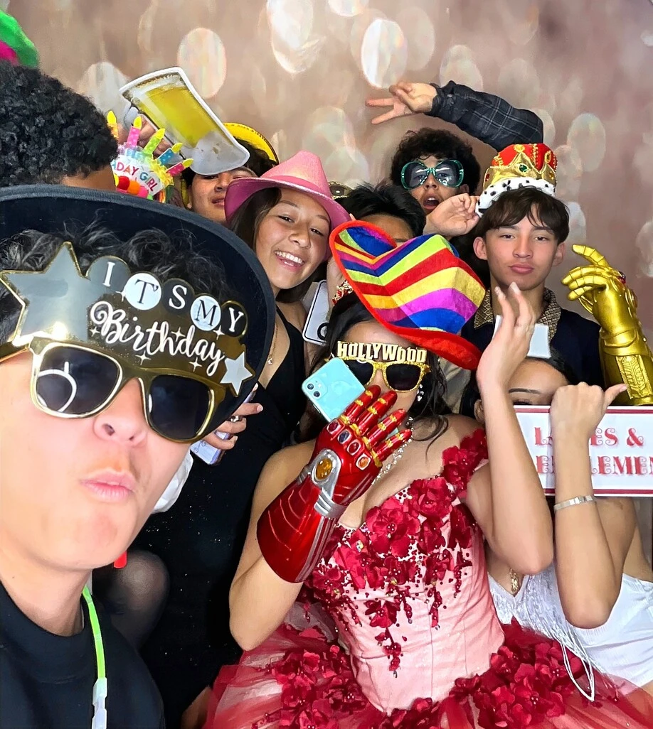 Guests pose with playful photo booth props at a birthday party.
