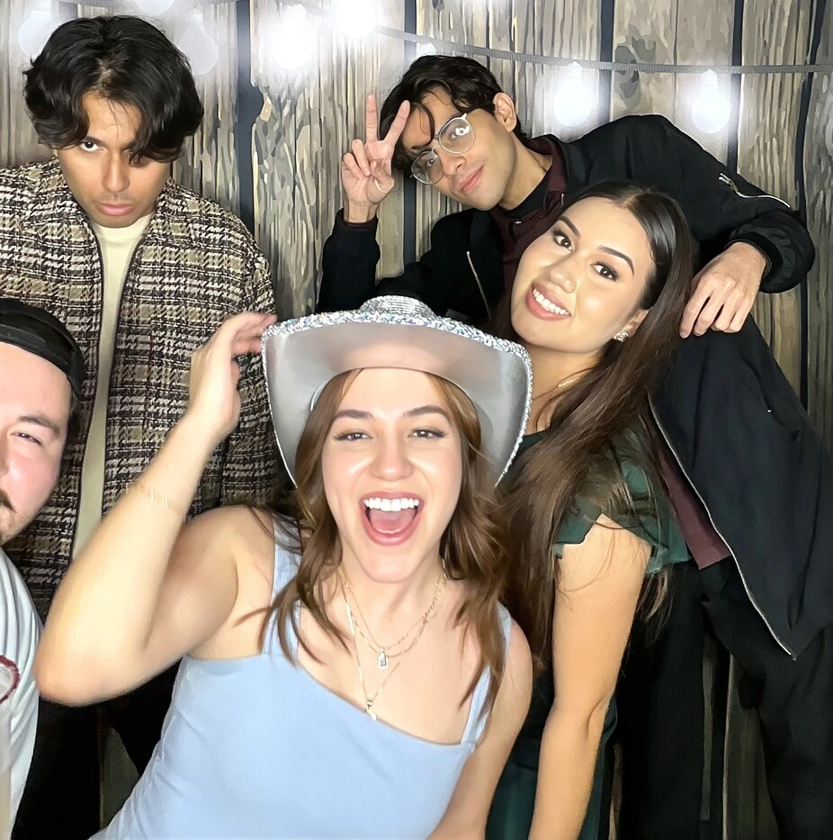 A family poses with playful photo booth props at a quinceañera celebration.