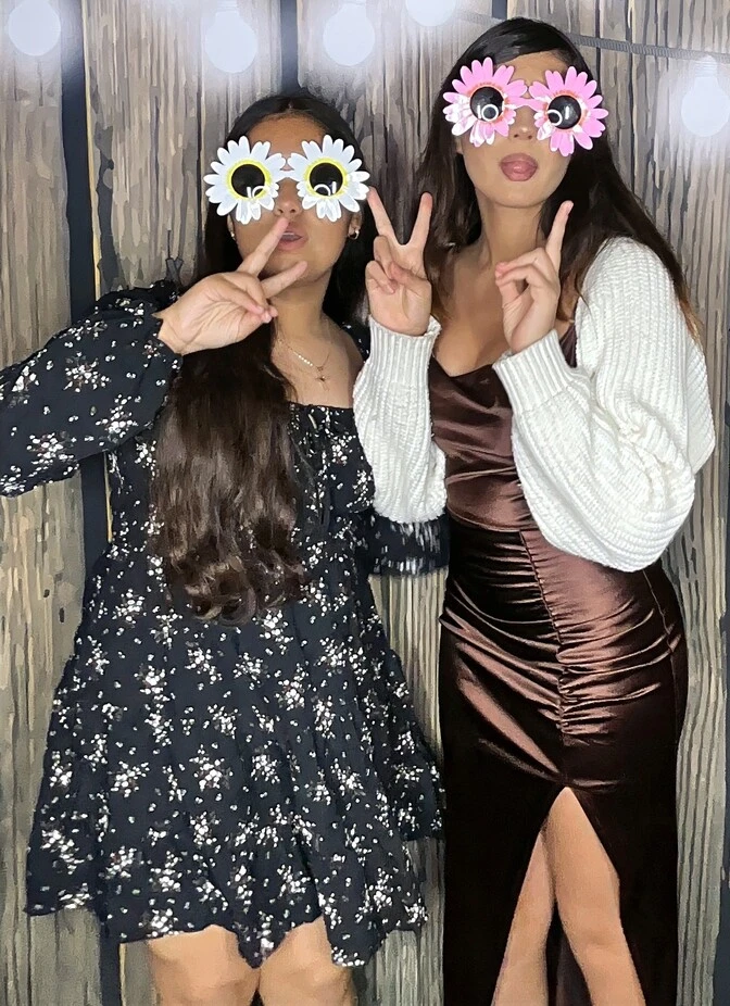 Friends pose with playful photo booth props at a quinceañera celebration.