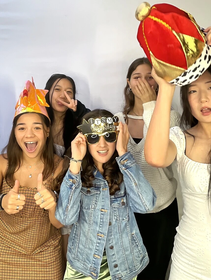 Guests pose with playful photo booth props at a Sweet 16 celebration.