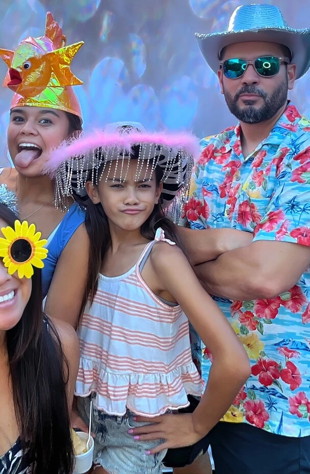 Guests pose with playful photo booth props at a tropical-themed party.