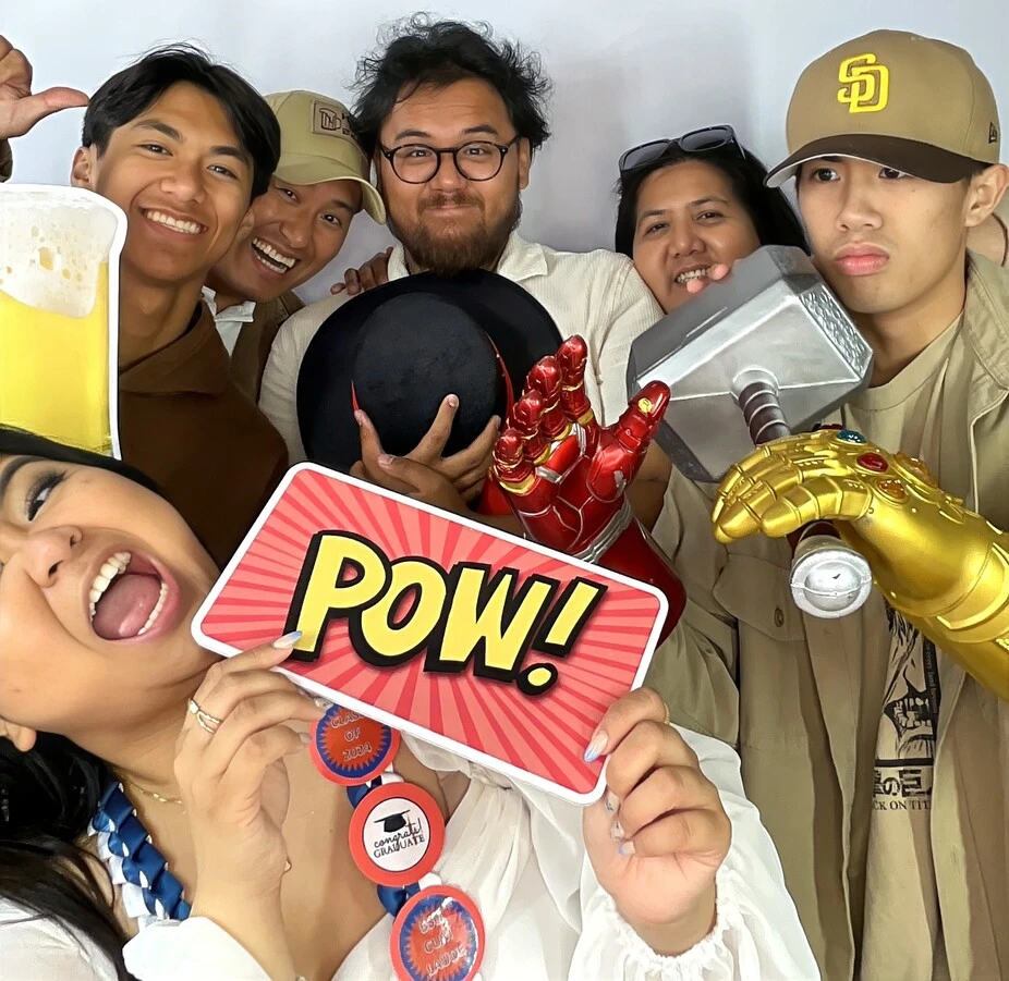 Guests pose with playful photo booth props at a graduation celebration.