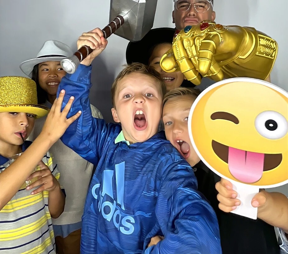 Children pose with playful photo booth props at a birthday party.