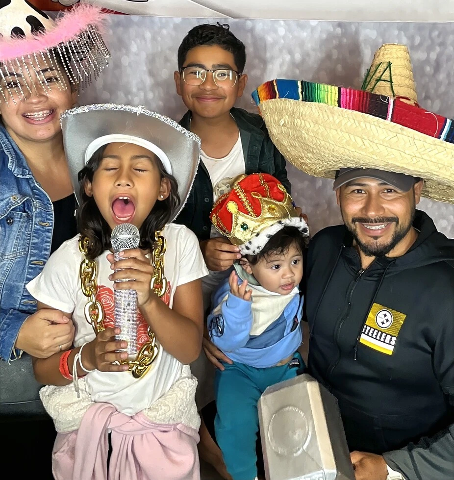 Guests pose with playful photo booth props at a fiesta-themed celebration.