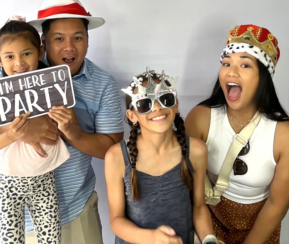 A family poses with playful photo booth props at a family celebration.