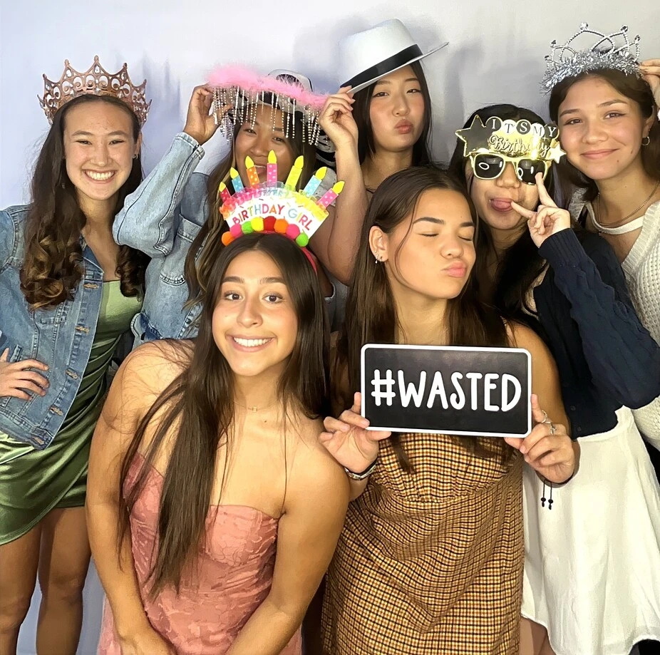 Teen friends pose with playful photo booth props at a Los Angeles celebration.