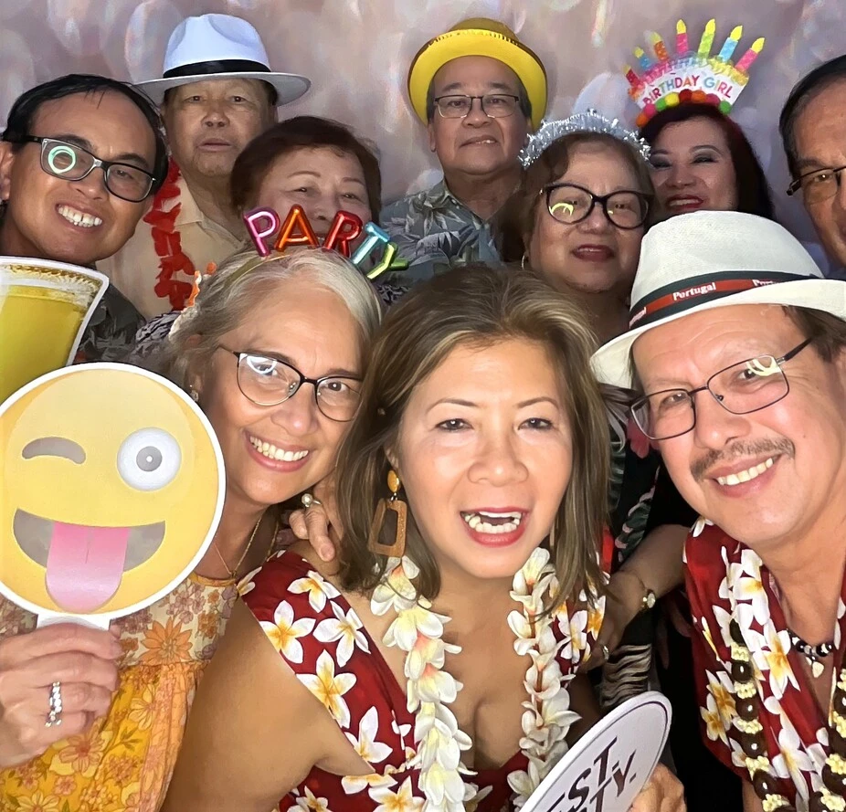 Guests pose with playful photo booth props at a tropical-themed party.