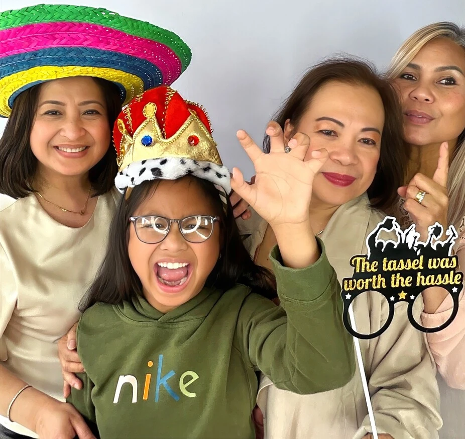 Guests pose with playful photo booth props at a graduation celebration.