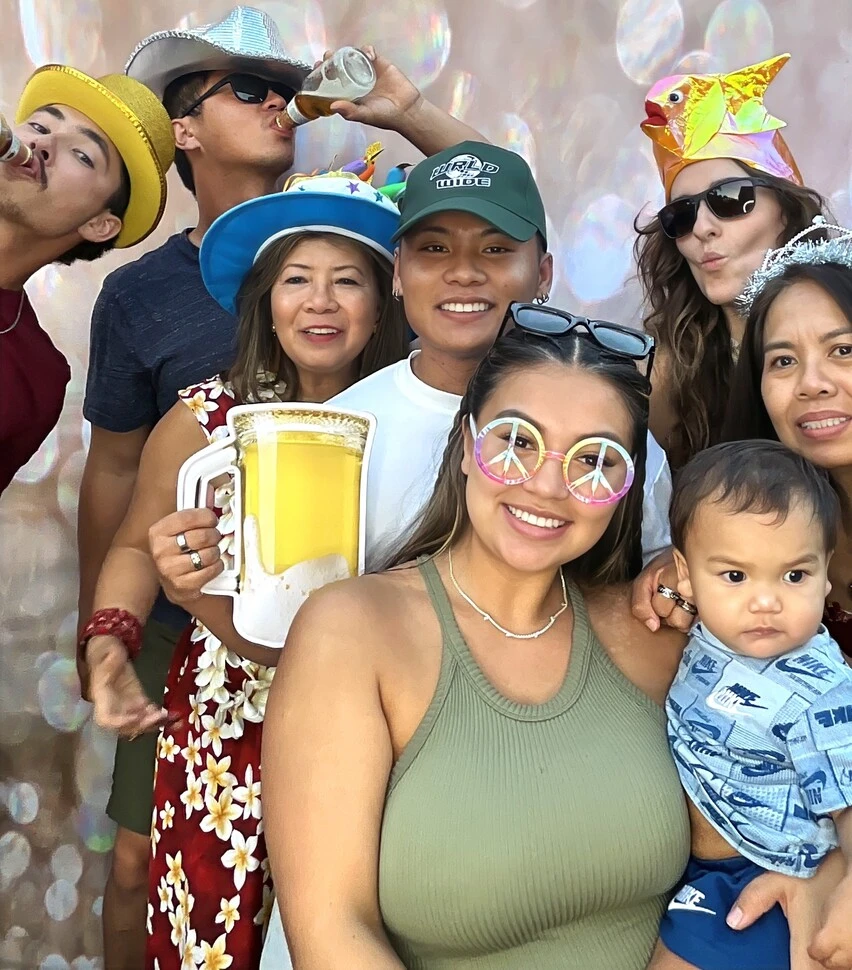 Guests pose with playful photo booth props at a tropical-themed party.