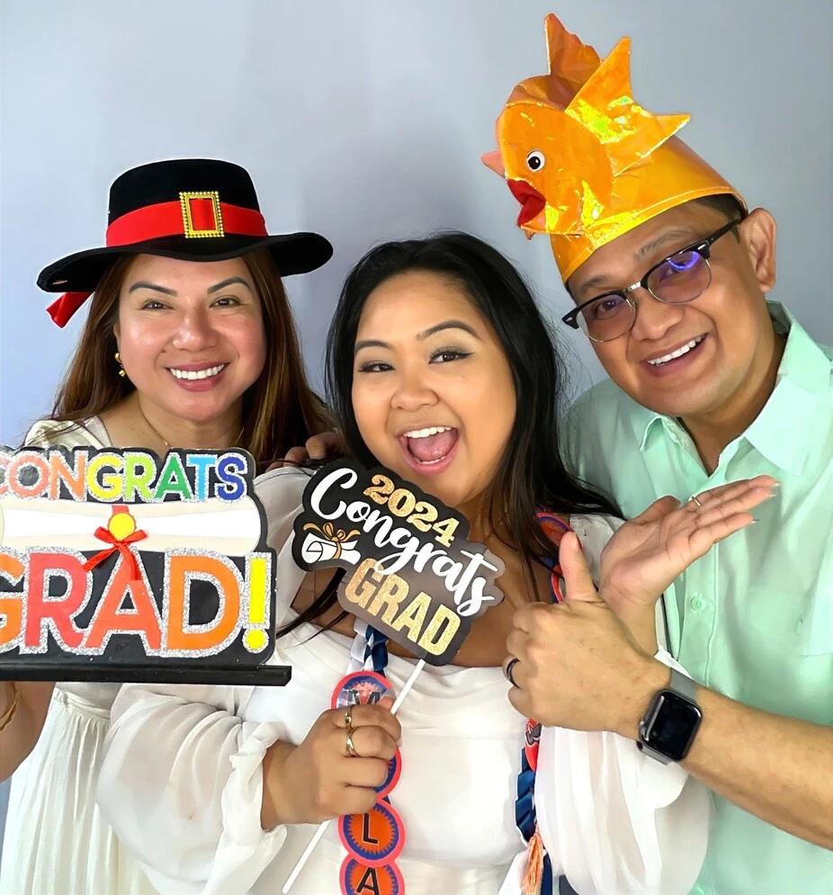 Guests pose with playful photo booth props at a graduation celebration.