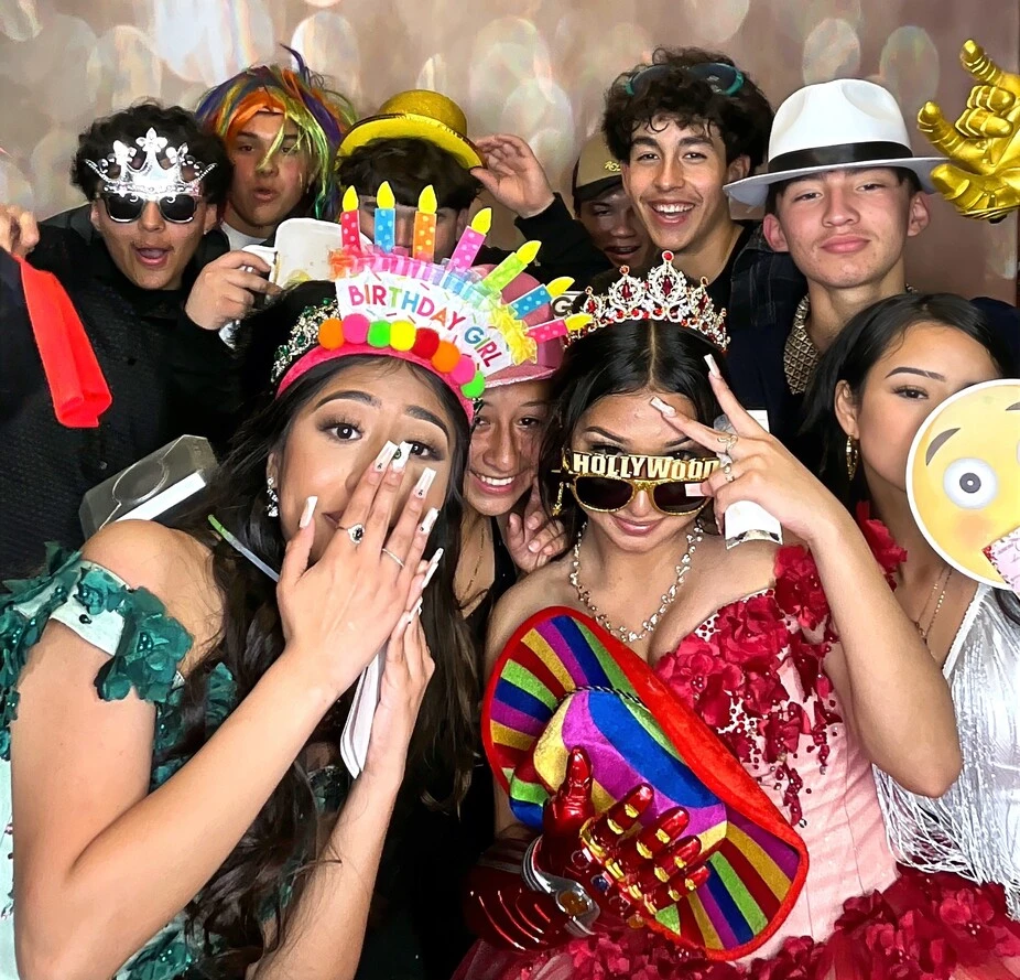 Guests pose with playful photo booth props at a Sweet 16 celebration.